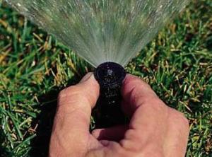 a Federal Way Irrigation tech hand adjusting the spray angle of a pop up head